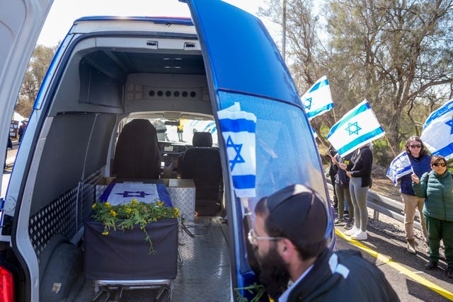 Mourners gather around the car carrying the coffin of former Israeli hostage Oded Lifshitz at the entrance of Kibbutz Nir Oz