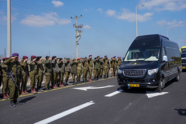 Israeli soldiers salute as the convoy carrying the coffins of slain hostages Shiri Bibas and her two children, Ariel and Kfir