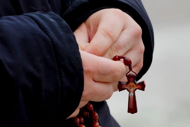 A man holds rosary beads as he prays for Pope Francis 