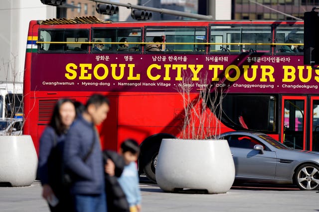 People walk near a tour bus in Seoul, South Korea