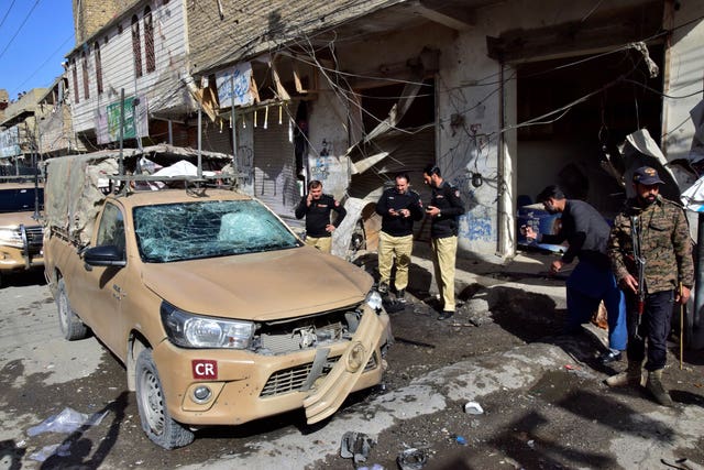 Security officials examine a damaged security forces’ vehicle at the site of a bomb blast