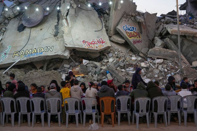 People sitting at a table amid huge chunks of rubble