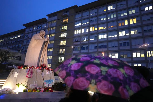 People shelter from the rain as they pray for Pope Francis in front of the Agostino Gemelli Polyclinic in Rome, where the Pontiff has been in hospital since February 14 