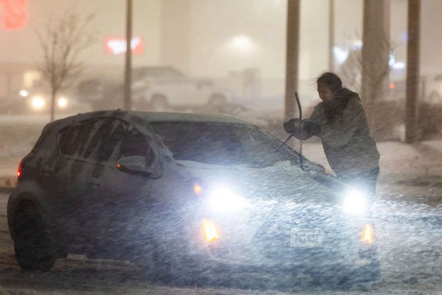 A motorist adjusts their windshield wipers near Saddle Creek Road and Leavenworth Street during a blizzard warning in Omaha