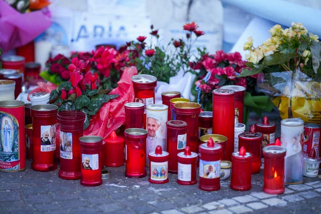 Candles and flowers for Pope Francis are laid in front of the hospital where he is being treated