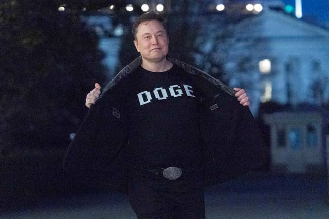 Elon Musk flashes a DOGE T-shirt to the media at the White House