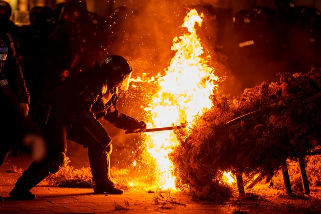 A police officer attempts to extinguish a fire in a bush