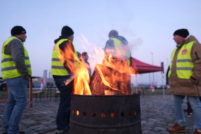 Participants in a warning strike stand at a fire barrel in front of Leipzig-Halle Airport in Schkeuditz