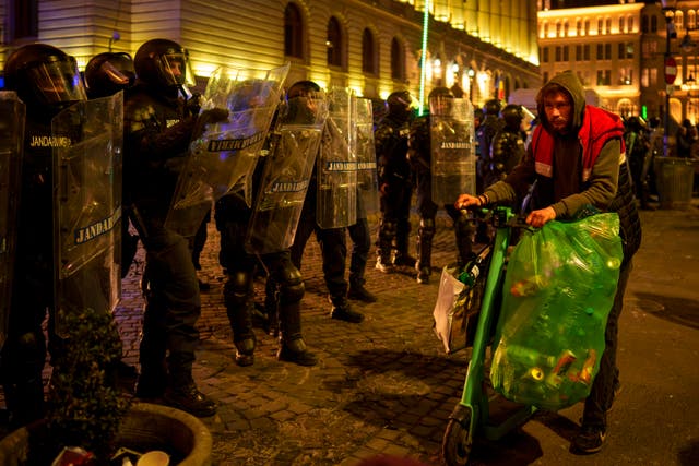 A man walks by riot police in Busharest