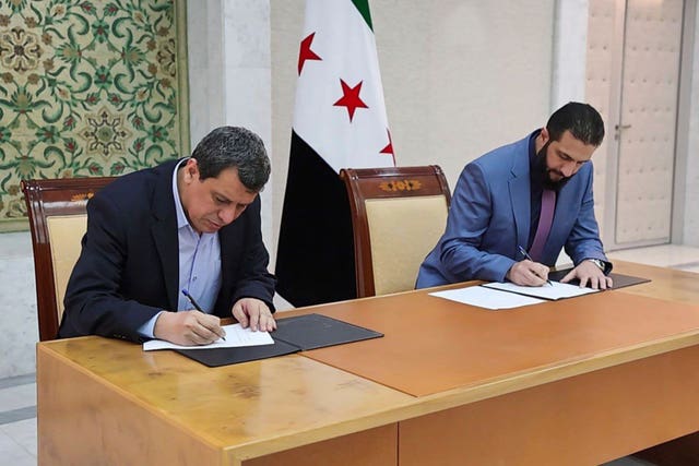 Syria’s interim President Ahmad al-Sharaa, right, and Mazloum Abdi, the commander of the US-backed Kurdish-led Syrian Democratic Forces, sign a deal in Damascus