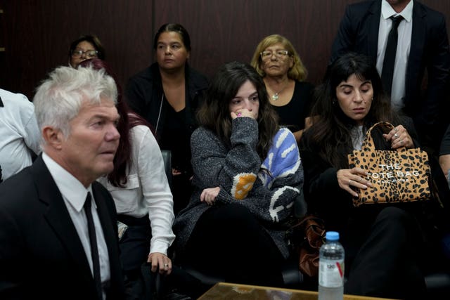 Dalma, centre, and Yanina Maradona, daughters of late soccer star Diego Maradona, sitting in court