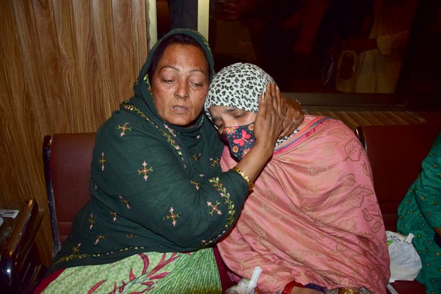 Passengers rescued by security forces from a passenger train attacked by insurgents comfort each other upon their arrival at a railway station in Quetta,