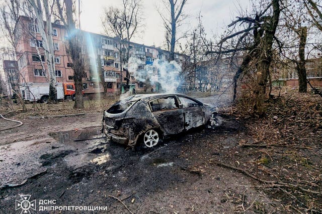 In this photo provided by the Ukrainian Emergency Service, a burned car and damaged residential buildings are seen after a Russian missile hit the area, in Kryvyi Rih