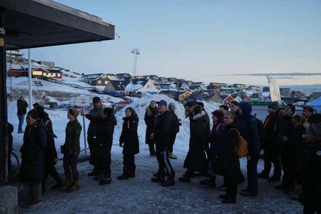 People line up outside a polling station to cast their vote in parliamentary elections in Nuuk, Greenland