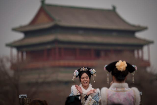 Chinese girls dressed in Qing Dynasty attire take pictures with the background of Drum Tower at Shichahai in Beijing