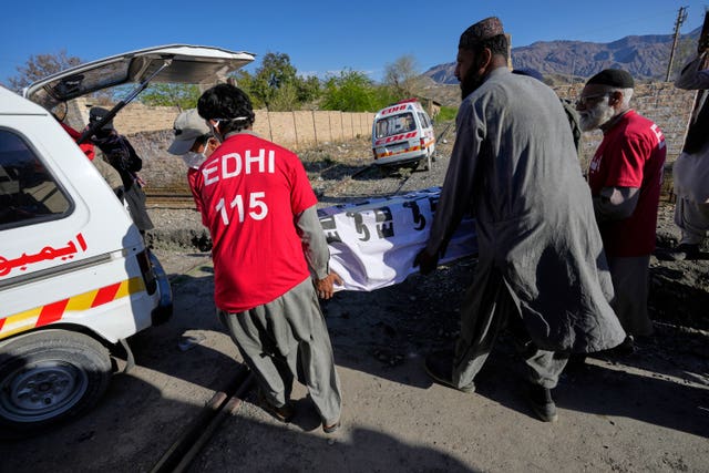 Rescue workers transport a coffin containing the body of a victim from a the train attack 