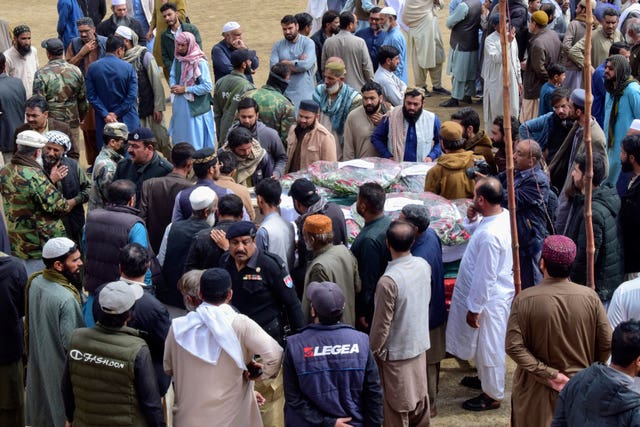 Mourners gather around a casket of a victim of the train attack in Quetta