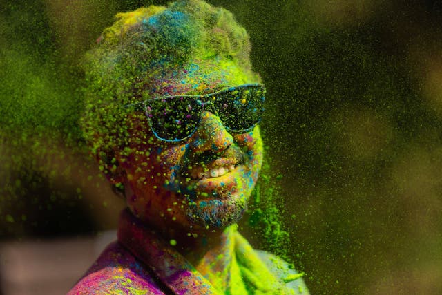 A man with his face smeared with green and yellow powder smiles