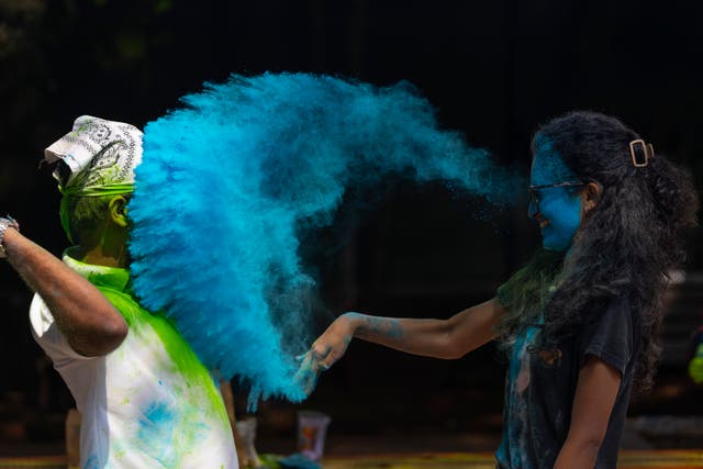 A girl throws colored powder on her friend