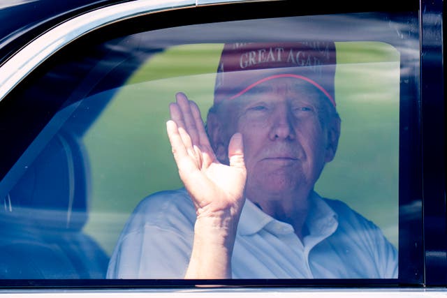 President Donald Trump waves from his limousine as he leaves Trump International Golf Club on Saturday in West Palm Beach