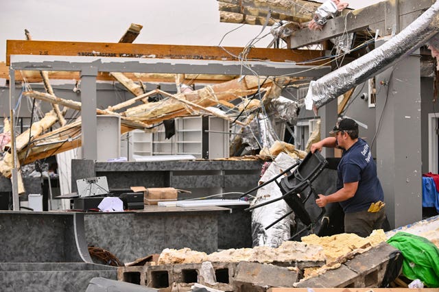 Dustin Halcom of the Cord Fire Department helps salvage what is left of the Walling Drug store in Cave City, Arkansas