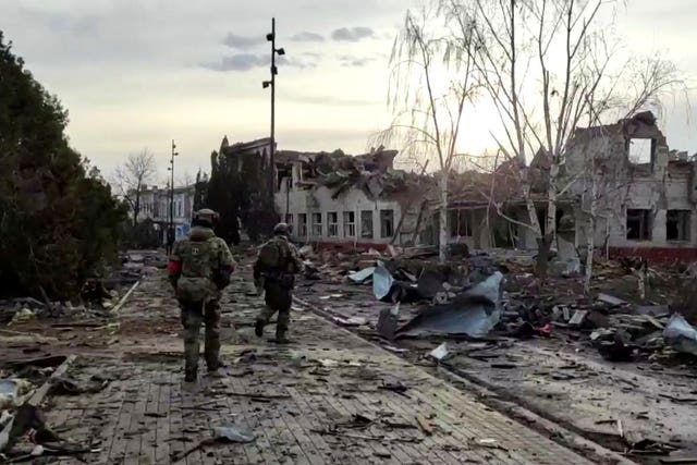 Two soldiers walk in a destroyed street