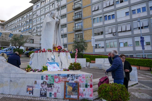 People praying at a makeshift memorial outside a hospital