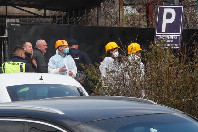 A group of people, including some wearing masks and protective clothing, outside a building