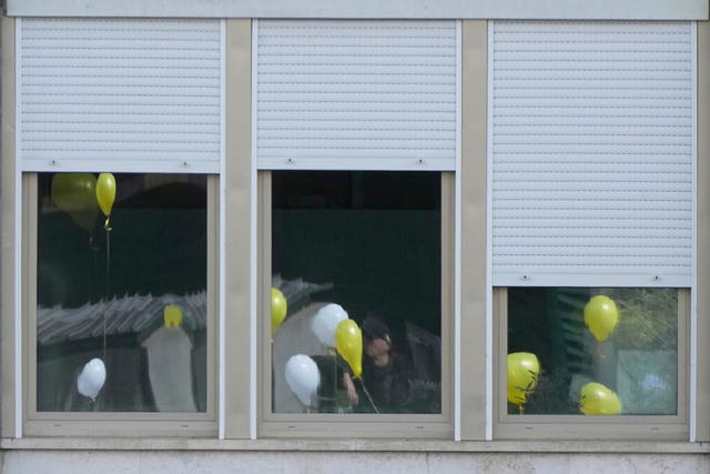 Balloons with the colours of the Vatican flag are reflected on the windows of the Gemelli hospital 