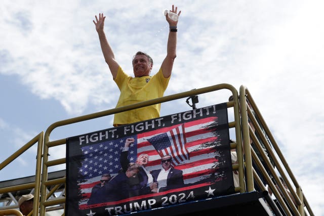 Brazil’s former president Jair Bolsonaro gesturing above a Donald Trump poster