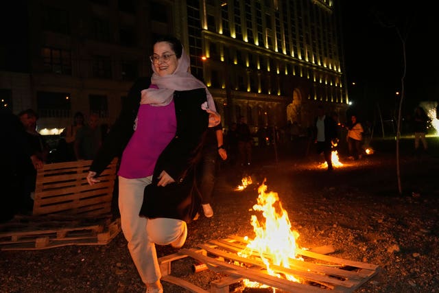 An Iranian woman jumps over a bonfire celebrating Chaharshanbe Souri