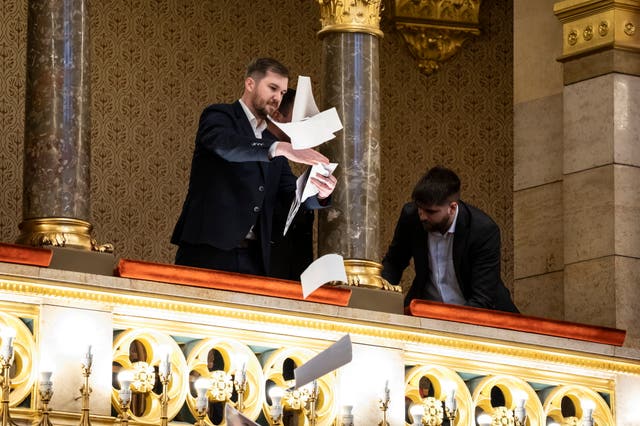 A man throws pamphlets from a balcony