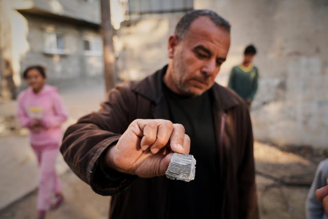 A man shows what he said was shrapnel from a projectile that struck a UN guesthouse, leaving one staff member dead and five others injured in Deir al-Balah, central Gaza 