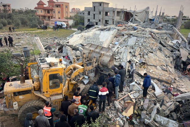 Volunteers and rescue workers use a bulldozer to remove the rubble of a building hit by an Israeli army airstrike in Khan Younis 