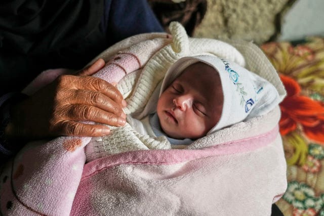 Ella Osama Abu Dagga, 25 days old, is held by her great-aunt Suad Abu Dagga, after she was pulled from the rubble earlier following an Israeli army airstrike that killed her parents and brother, in Khan Younis