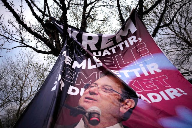 A man attaching a banner of Istanbul’s Mayor Ekrem Imamoglu to a tree