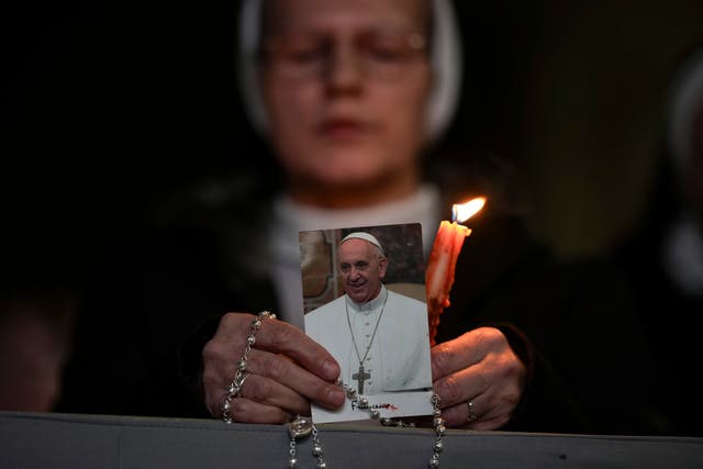 A nun holds a candle and an image of Pope Francis