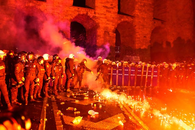 A police officer kicks a flare thrown by protesters