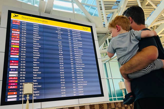 A man and child look at cancelled flight information