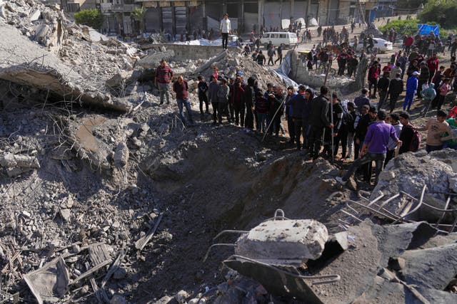 Palestinians inspect a site hit by an Israeli strike in Gaza City