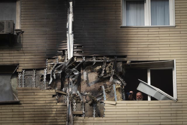 A burnt out apartment window with a person visible cleaning up