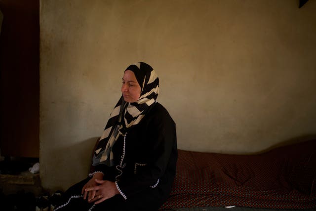 Lamia Ballal, wife of Oscar winner Hamdan Ballal, sits on a bed