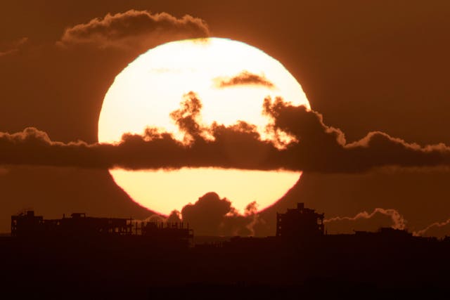 The sun sets behind buildings destroyed during the Israeli ground and air offensive in the Gaza Strip as seen from southern Israel