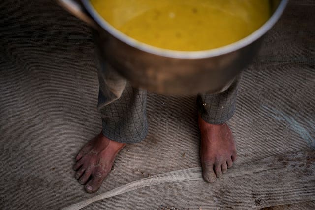 A Palestinian child carries a pot of soup