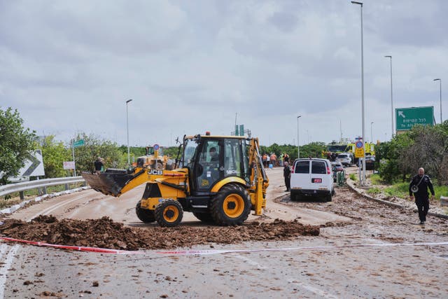 Israeli security forces clean the road from debris where the Israeli military said a projectile fired by Yemen’s Houthi rebels landed in the area of Ben Gurion International Airport near Tel Aviv on Sunday