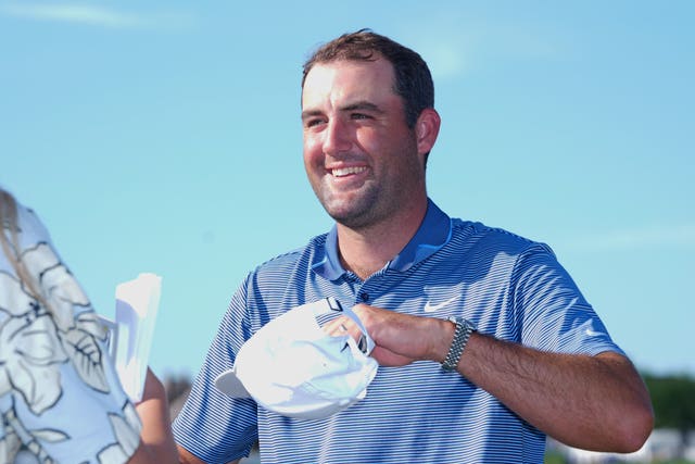 Scottie Scheffler, with his cap in his left hand, smiles