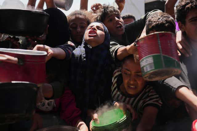 Palestinians struggle to get donated food at a community kitchen in Khan Younis in the Gaza Strip 