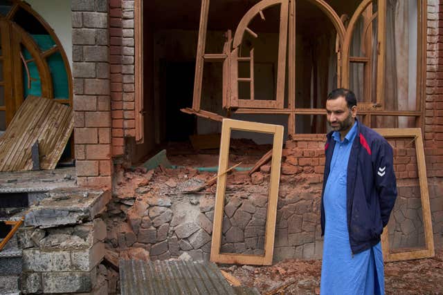 A Kashmiri villager stands outside his damaged house after overnight shelling from Pakistan at Gingal village in Uri, Indian controlled Kashmir 