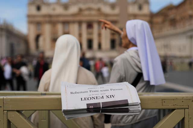 Nuns stand next to copies of L’Osservatore Romano newspaper with headlines in Latin of Pope Leo XIV at the Vatican,