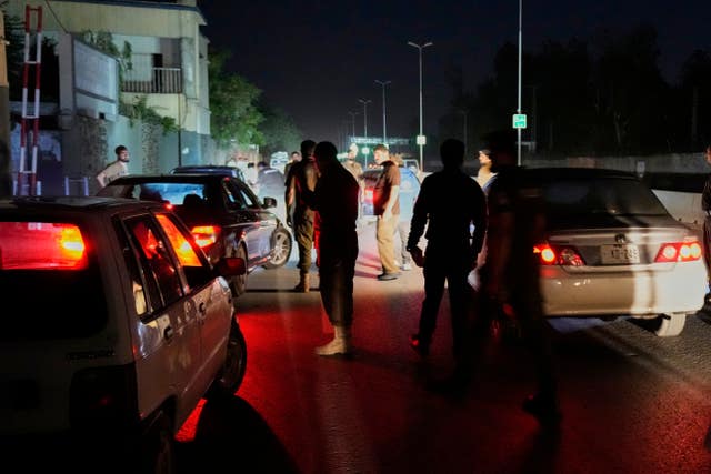 Pakistani police officers remove vehicles and people from the main entry of Nur Khan airbase following an Indian missile strike in Rawalpindi